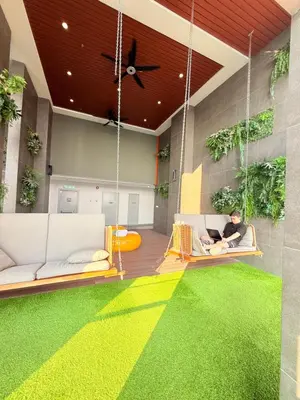 a person sitting on a swing in a room with a green rug at COzy Suite KL Sentral By Riveria City in Kuala Lumpur