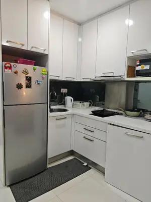 a kitchen with white cabinets and a refrigerator at Summer Suites Klcc by Sikka in Kuala Lumpur