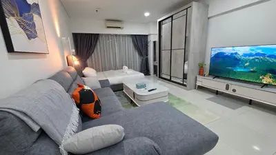 a living room with a gray couch and a large tv at Summer Suites Klcc by Sikka in Kuala Lumpur