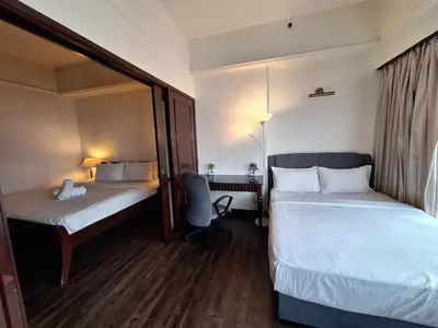 a hotel room with two beds and a chair at KL Times Square Hotel Service Suite in Kuala Lumpur