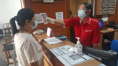 a man wearing a mask giving a woman a card at Cardogan Hotel in Kuala Lumpur