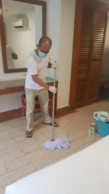 a man in a mask cleaning a room with a mop at Cardogan Hotel in Kuala Lumpur