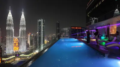 a man standing on the edge of a rooftop pool with a city skyline at Imperial Residences KLCC - MK HOME in Kuala Lumpur