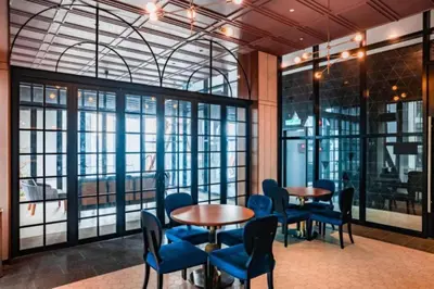 a room with two tables and blue chairs and windows at KLCC Scarletz Residence Near By KL in Kuala Lumpur
