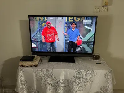 two men standing in front of a television on a table at Baiduri Homestay in Kuala Lumpur