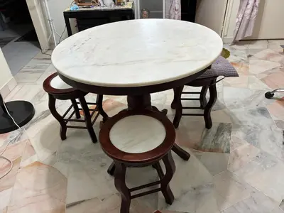 a wooden table with four chairs and a white marble table at Baiduri Homestay in Kuala Lumpur