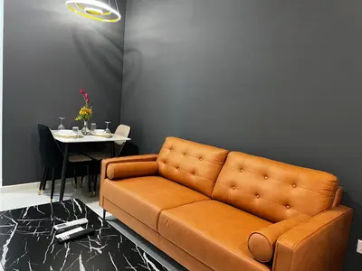 a brown leather couch in a living room with a table at The Majestic Gen Luxury Suites KLCC in Kuala Lumpur