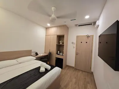 a bedroom with a bed and a desk and a door at The Backpackers Hut Chow Kit in Kuala Lumpur