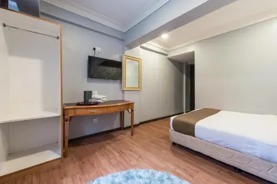 a bedroom with a bed and a desk and a bed and a table at Hotel Grand Orchard in Kuala Lumpur
