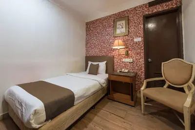 a hotel room with a bed and a chair at Hotel Grand Orchard in Kuala Lumpur