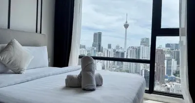 a teddy bear sitting on a bed in front of a window at Bukit Bintang in Kuala Lumpur