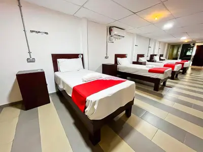a room with four beds with red sheets at J Hotel Masjid India KL in Kuala Lumpur