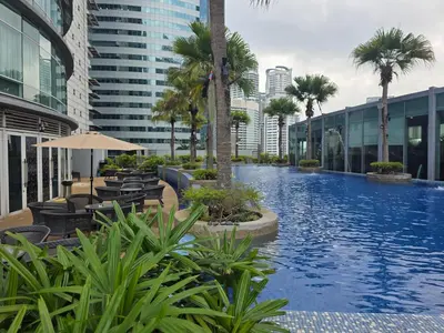 a large swimming pool with palm trees and buildings at Vortex suites klcc by musab in Kuala Lumpur
