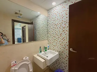 a woman taking a picture of a bathroom with a sink at Spacious Family 2BR Balcony Comfy Regalia Suites in Kuala Lumpur