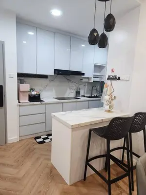 a kitchen with white cabinets and a counter and two chairs at Yasemin Homestay in Kuala Lumpur