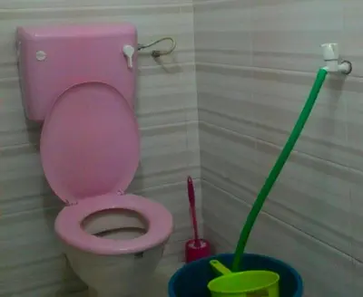 a pink toilet with a mop in a bathroom at Zam Zam Homestay in Kuala Lumpur
