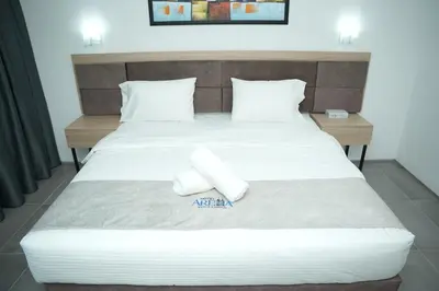 a bed with white sheets and pillows on it at Arena Suites Kuala Lumpur in Kuala Lumpur
