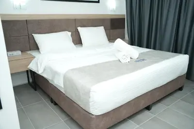 a bed with white sheets and pillows in a room at Arena Suites Kuala Lumpur in Kuala Lumpur