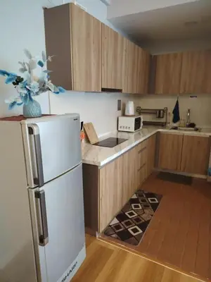 a kitchen with wooden cabinets and a white refrigerator at Regalia residence suite view in Kuala Lumpur
