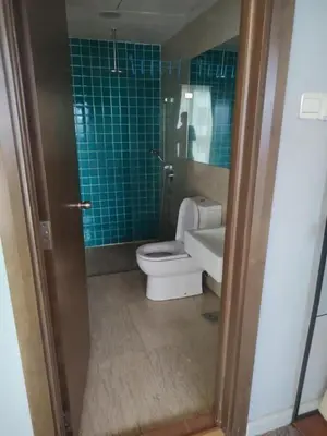 a bathroom with a toilet and a sink and blue tiles at Regalia residence suite view in Kuala Lumpur