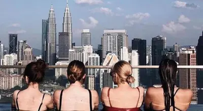 three women in bikinis looking at a city skyline at Regalia residence suite view in Kuala Lumpur