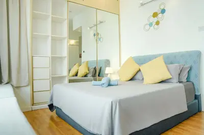 a bedroom with a large white bed with yellow pillows at A Cozy & Comfy Studio in KLCC with KL Tower View in Kuala Lumpur