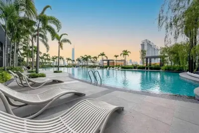 a swimming pool with white chairs and palm trees at Trion KL at Level 57 in Kuala Lumpur