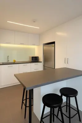 a kitchen with white cabinets and a counter with two stools at Mindful Bangsar Loft KL Sentral Mid Valley The Gardens Pasar Seni in Kuala Lumpur