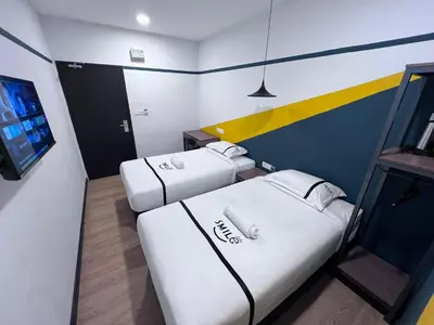 two beds in a small room with a tv at Seeds Hotel PV12 in Kuala Lumpur