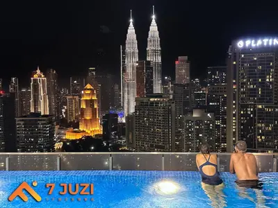 two people in a swimming pool with a city skyline at KLCC Cozy Suite 21F with Best View Infinity Pool in Kuala Lumpur