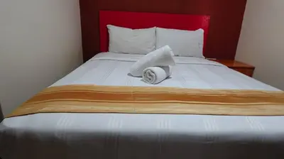 a bed with a red headboard with a towel on it at Hotel Wings Kuala Lumpur in Kuala Lumpur