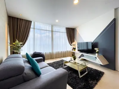 a living room with a gray couch and a tv at The Luxury Penthouse KLCC in Kuala Lumpur