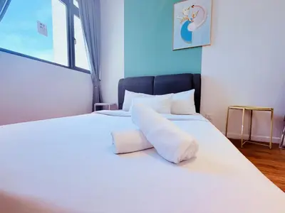 a white bed with a rolled up towel on it at Chamber Luxury Serviced Suites KL in Kuala Lumpur