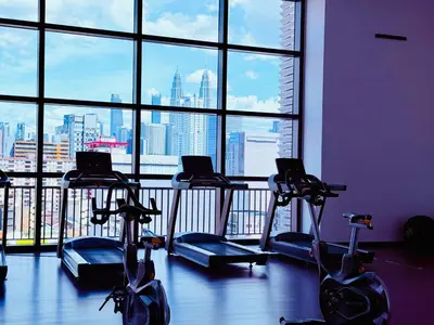 a gym with several tread machines in front of a window at Chamber Luxury Serviced Suites KL in Kuala Lumpur