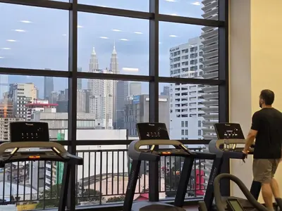 a man standing in a gym looking out the window at the city at GRAND Suites Chamber AT Klcc in Kuala Lumpur