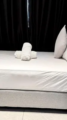 a bed with white sheets and pillows on it at Visitors Axon Residence Bukit Bintang KL City Center in Kuala Lumpur