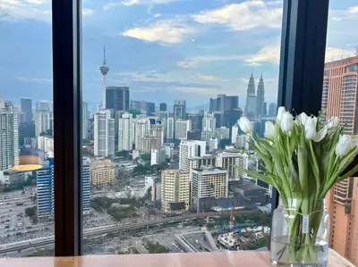 a vase of white flowers sitting on a table in a window at 3 Towers Urban Studio Apartment in Kuala Lumpur