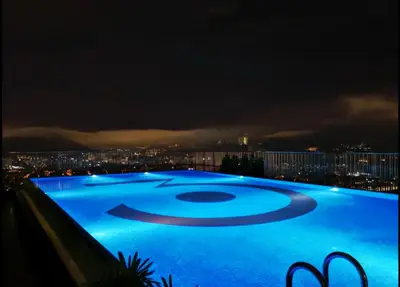 a swimming pool at night with a city in the background at 3 Towers Urban Studio Apartment in Kuala Lumpur