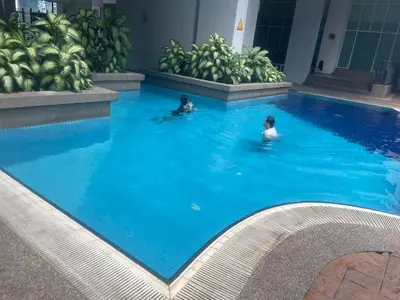 two people swimming in a large blue swimming pool at Sky suite at Seri Bukit Ceylon in Kuala Lumpur