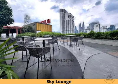 a patio with tables and chairs and a city skyline at Majestic Residence Kuala Lumpur by Cityscape in Kuala Lumpur
