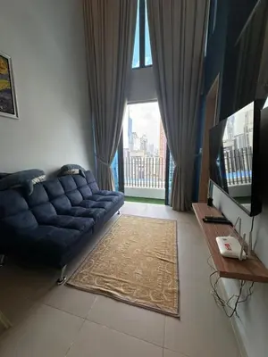 a living room with a blue couch in front of a window at The Colony By Infinitum With Rooftop Pool in Kuala Lumpur