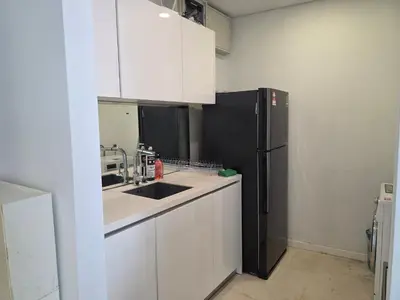 a kitchen with white cabinets and a black refrigerator at Vortex suites klcc by KAZI in Kuala Lumpur