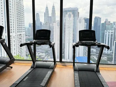 a gym with two treadying machines in front of a window at The Majestic Residence KLCC By Castle in Kuala Lumpur