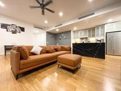 a living room with a brown couch and a kitchen at St Mary Residence by PILLOWTALKS in Kuala Lumpur