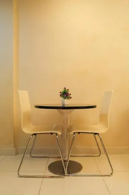 a table with two chairs and a vase with flowers on it at KL Hartamas Studio, Wifi Smart TV in Kuala Lumpur