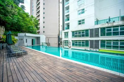 a swimming pool with chairs and an umbrella next to a building at Lux Studio Plaza Damas Kuala Lumpur KL in Kuala Lumpur