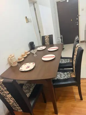 a dining room table with chairs and a wooden table with plates at PARKVIEW RESIDENCE KLCC By IKNAS SUITES in Kuala Lumpur