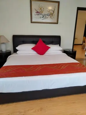 a bed with a red pillow on top of it at BBS Suites At Times Square in Kuala Lumpur