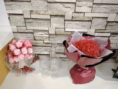 a table with two vases of roses and wine glasses at KL studio with Private Jacuzzi in Kuala Lumpur