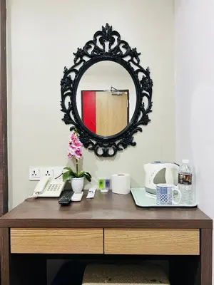 a wooden desk with a mirror and a table with a keyboard at Elite Hotel KL Sentral in Kuala Lumpur